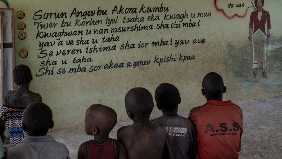 Niños frente a un cartel escrito en la pared en una lengua local africana de la región de Nigeria.