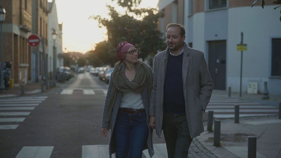 un hombre y una mujer agarrados de la mano paseando por una calle