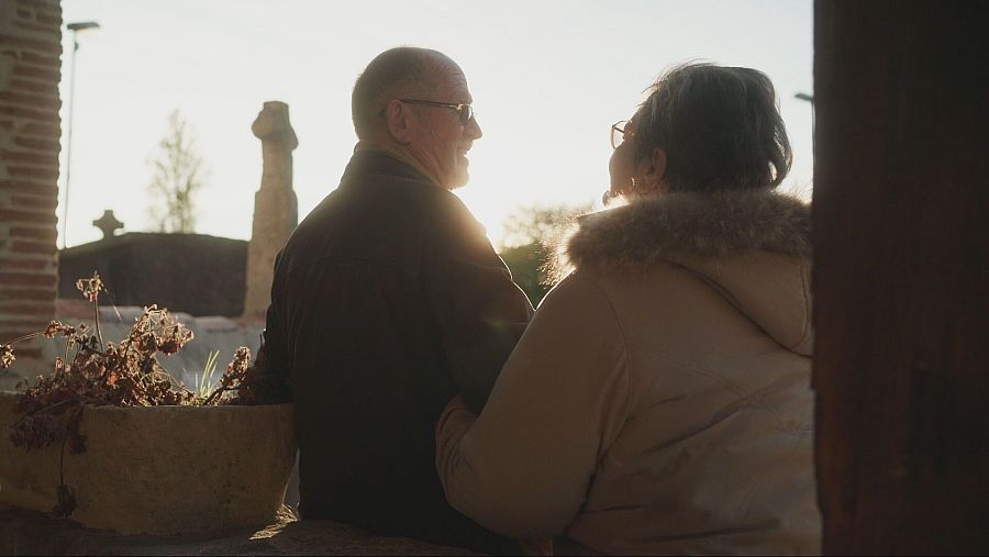 Mujer agarra por el brazo a hombre a contraluz y con cruz en detrás