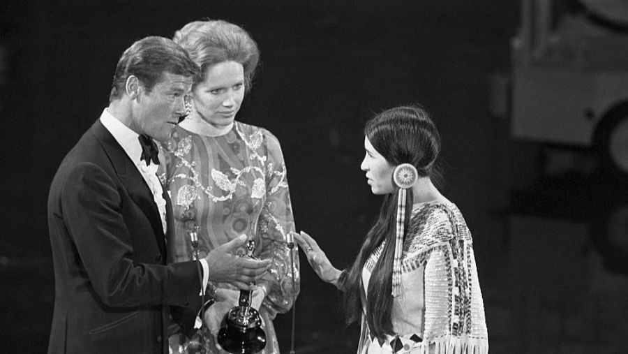 Roger Moore y Liv Ullmann escuchan a Sacheen Littlefeather