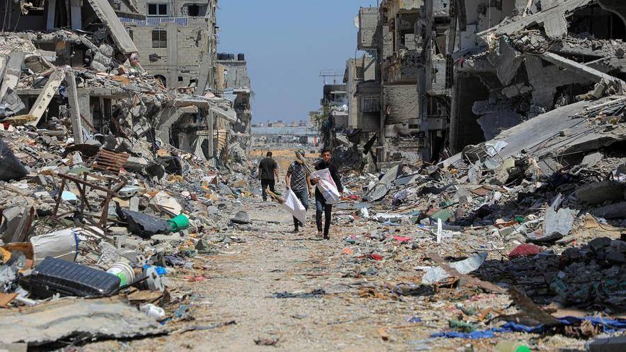 Palestinos caminan entre edificios destruidos por los bombardeos del Ejército de Israel contra la ciudad de Jan YUnis, en el sur de la Franja de Gaza.