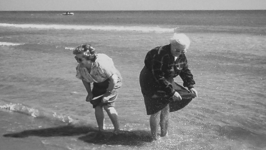 Dos mujeres mojándose los pies en la playa.