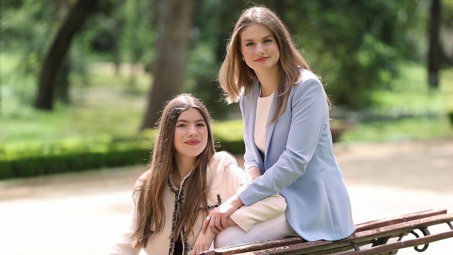 La princesa Leonor y la infanta Sofía sonríen a cámara sentadas en un banco