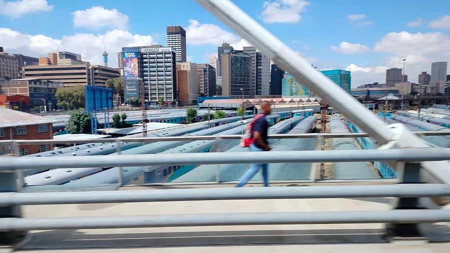 Un joven cruza el puente Nelson Mandela, en Johannesburgo, sobre decenas de trenes que no circulan por el colapso de la compañía ferroviaria