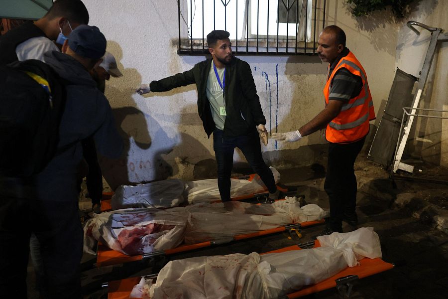 Sanitarios preparan los cuerpos de víctimas gazatíes del bombardeo de Israel sobre un campo de desplazados