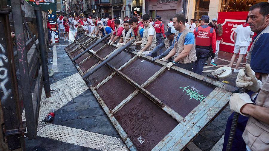 Un grupo de personas sujeta uno de los soportes laterales durante el último y octavo encierro de las fiestas de San Fermín 2023