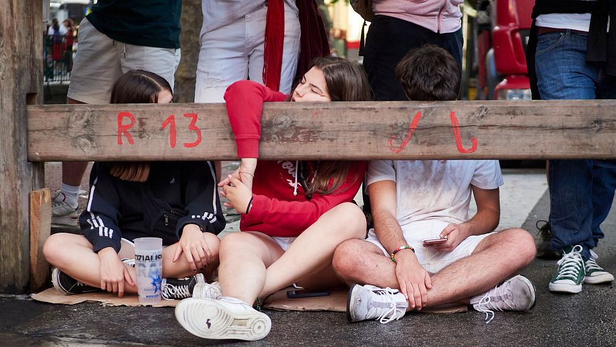 Varios jóvenes descansan en la barrera durante el séptimo encierro de las fiestas de San Fermín 2023