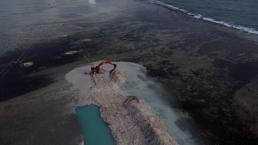 Vista aérea de una excavadora sacando tierra de una isla maldiva.