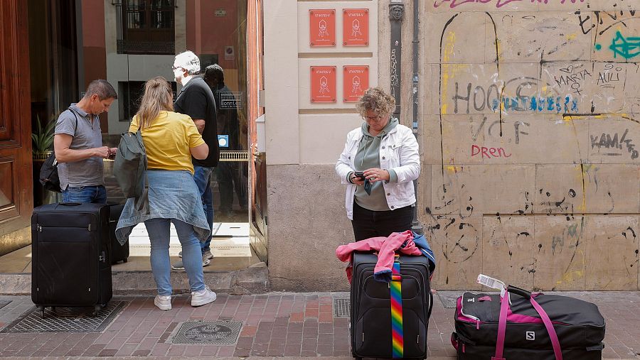 Un grup de turistes espera a l'entrada d'uns apartaments turístics a València