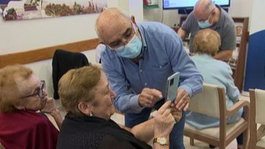 Un profesor del taller enseña a varias personas mayores a utilizar un smartphone