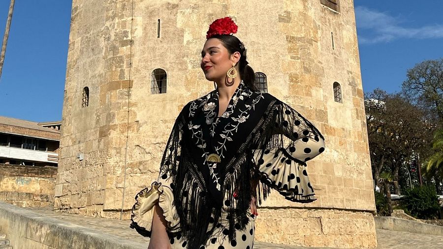 Mujer joven posa ante Torre del Oro de Sevilla vestida de flamenca