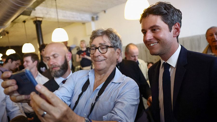 El primer ministro francés, Gabriel Attal, se toma una foto con un seguidor en una cafetería