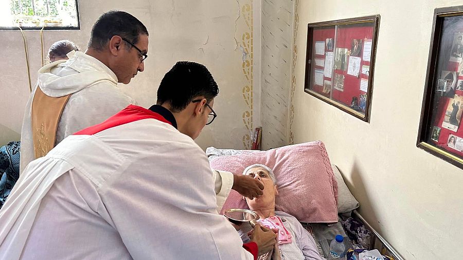 Una enferma refugiada en la parroquia recibe la comunión en su cama