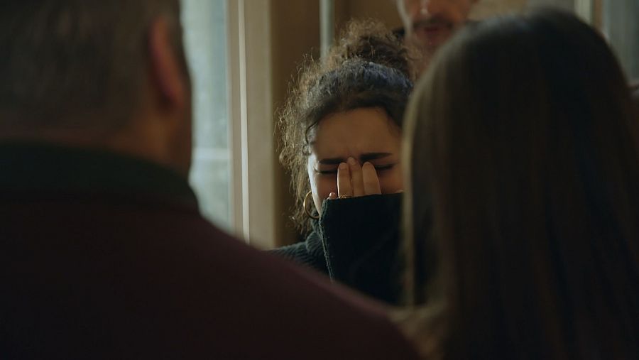 joven llorando y delante de ella un hombre y una mujer de espaldas