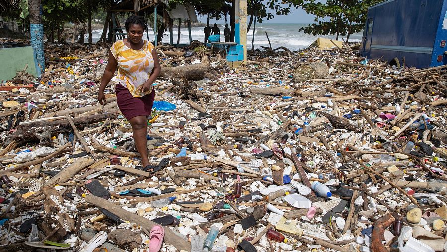 Una mujer camina por la playa Manresa, cubierta de basura tras el paso del huracán Beryl por Santo Domingo, República Dominicana