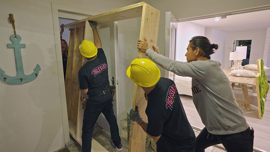 Julio se encuentra con su equipo de obreros, en casa de Arantxa ayudando a empujar un cabecero por una puerta donde no cabe