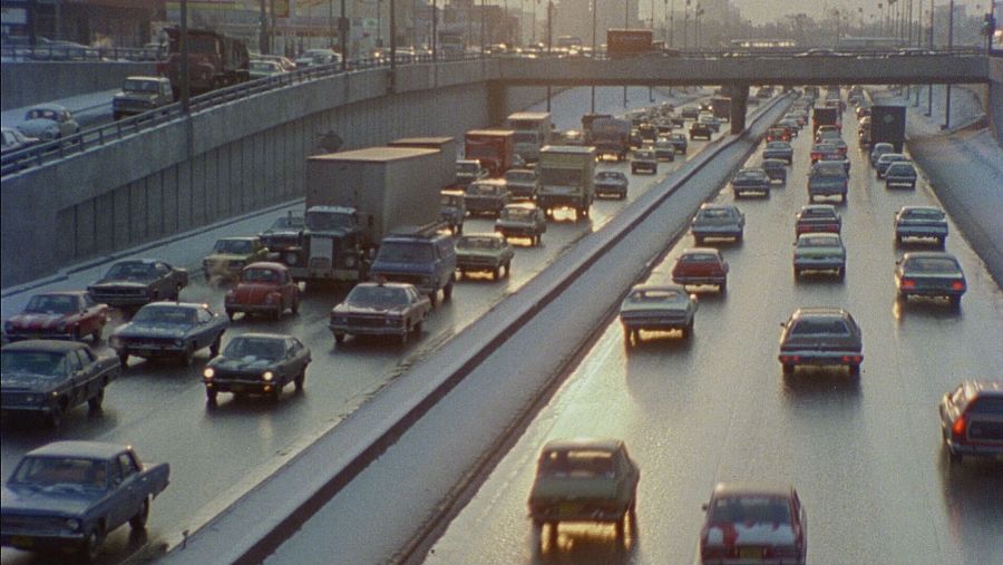 Fila de coches atascados  en carretera de los año setenta