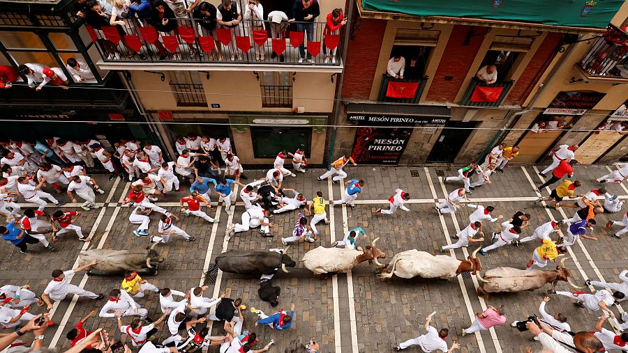 Los toros de José Escolar corren por la calle Estafeta rodeados de mozos.