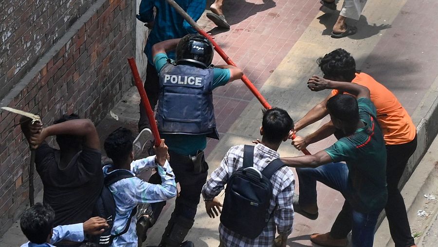 Manifestantes golpean a un policía durante un enfrentamiento en Daka, Bangladesh