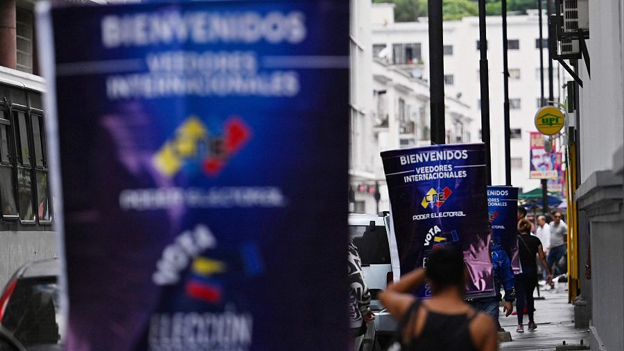 Un grupo de personas pasa junto a carteles del Consejo Nacional Electoral (CNE) en Caracas.