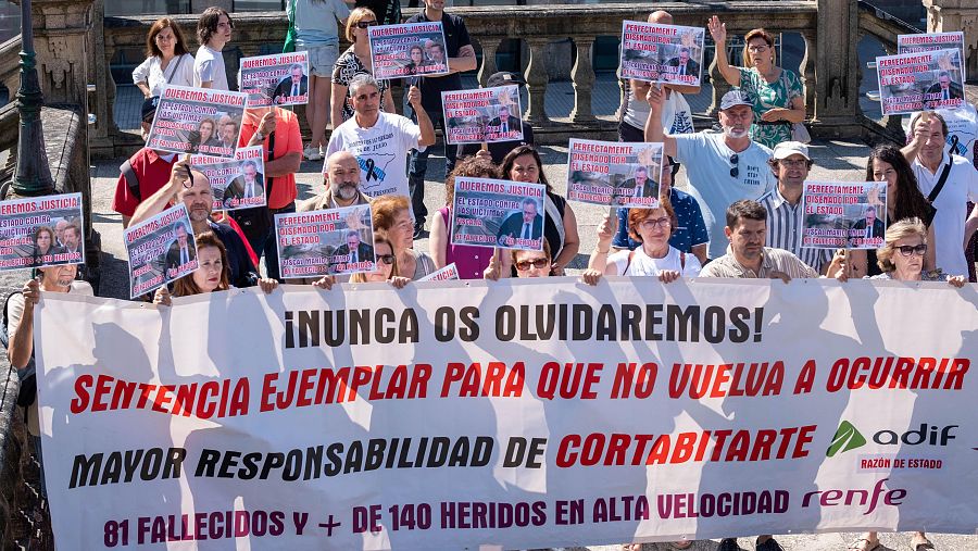 Varias personas con una pancarta y carteles durante una concentración de las víctimas de Angrois, en la estación de tren de Santiago, a 24 de julio de 2024, en Santiago de Compostela, A Coruña, Galicia (España).