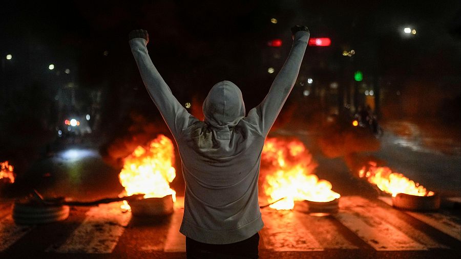 Un manifestante levanta los brazos frente a varios neumáticos en llamas en Caracas, Venezuela