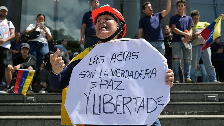 Una mujer sostiene una pancarta con la frase 