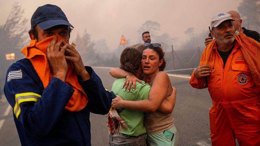 Mujeres se abrazan tras ser rescatadas durante el incendio forestal en Varnavas, al norte de Atenas. El incendio que amenaza Atenas sigue sin control y obliga a evacuar a decenas de miles de personas.