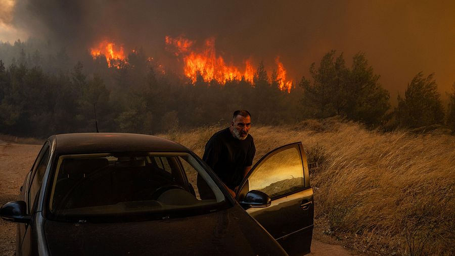 Un lugareño sube a su coche frente a las llamas para evacuar durante el incendio forestal en Dione este lunes. El incendio que amenaza Atenas sigue sin control y obliga a evacuar a decenas de miles de personas.