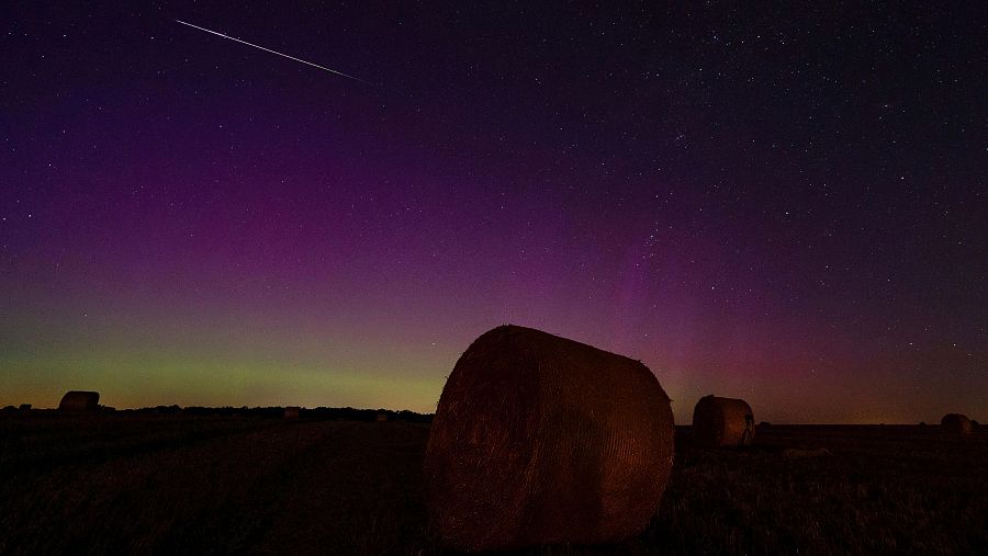 Una aurora brilla tras unos fardos de paja mientras una estrella fugaz cae en Betzin, Alemania