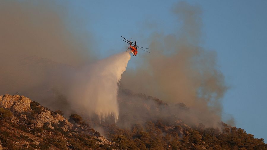 Un helicóptero de bomberos lanza agua en un rebrote cerca de Nea Makri, al este de Atenas (Grecia). Los incendios que rodean Atenas dejan una primera muerte.