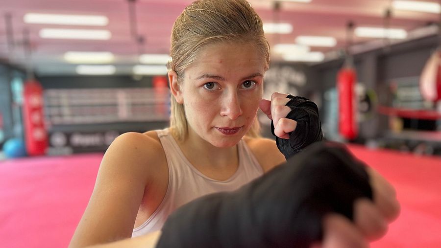 joven rubia con guantes entrenando en un gimnasio