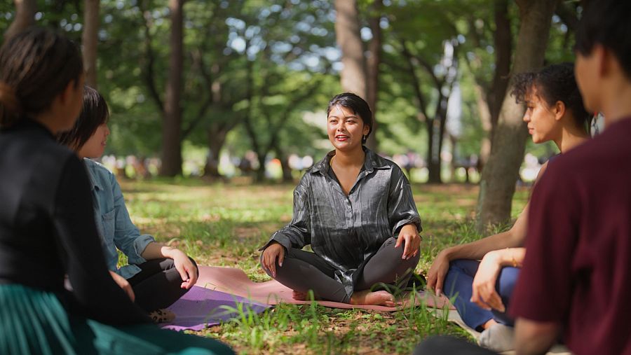 Grupo de personas practicando meditación en un bosque.