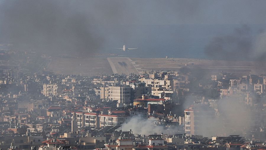 Un avión despega del aeropuerto de Beirut entre el humo de los bombardeos