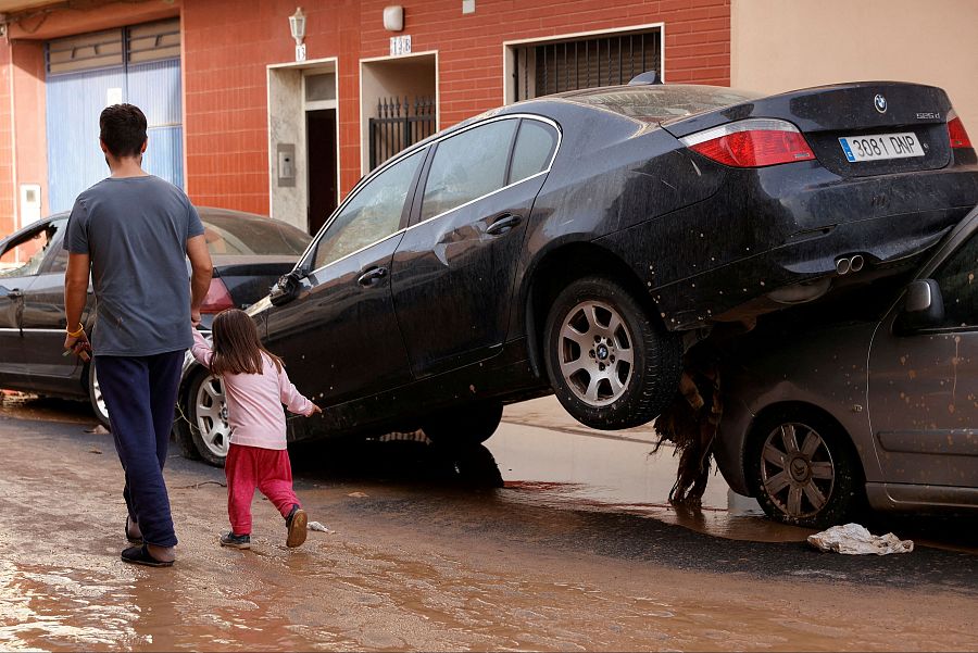 Un padre y una hija caminando entre los estragos de la DANA en Guadassuar, municipio de la Comunidad Valenciana