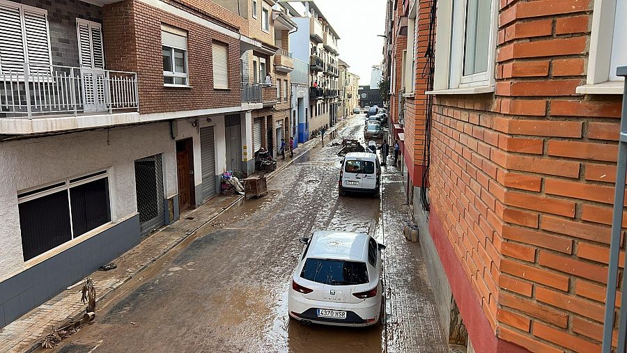 Los vecinos limpian la calzada en una de las calles de Massanassa