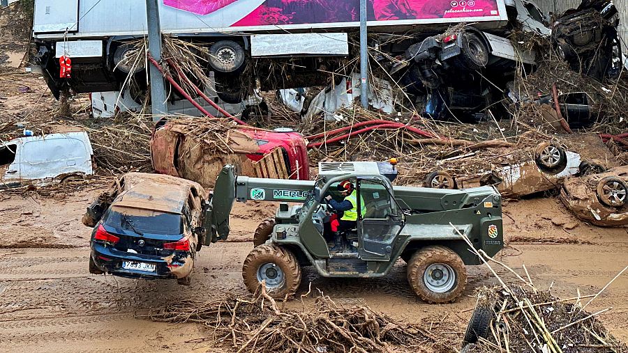 Un miembro de la UME aparta un coche destrozado por la DANA