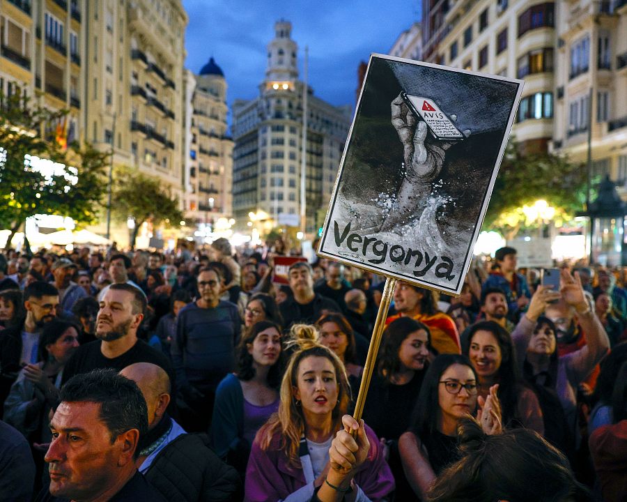 Un cartel muestra una mano hundida en el lodo sosteniendo un móvil con el aviso de Es-Alert y la palabra 