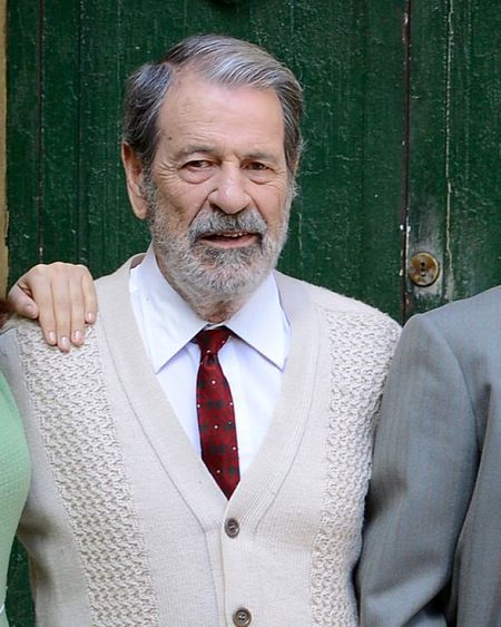 Retrato del actor Alejandro de la Madrid, con camisa blanca, corbata granate y cárdigan beige.