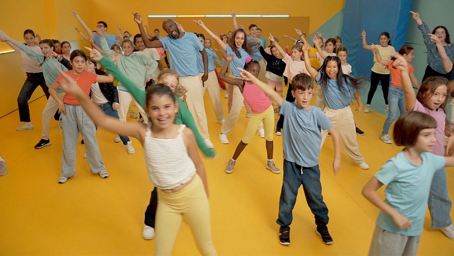 Grupo de niños de diversos países europeos bailando en un evento para fomentar la amistad.
