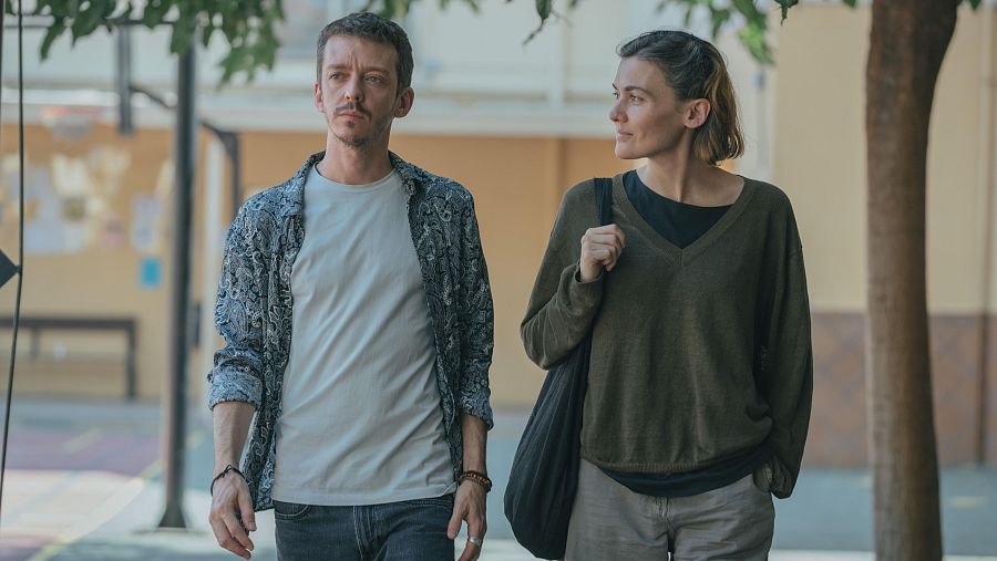 Fotograma de la serie 'La mitad de Ana' donde se puede ver a los actores Javier Rey y Veki Velilla caminando por un patio.