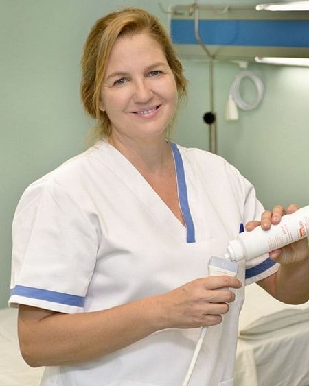 Sanitaria en uniforme aplica gel a un ecógrafo en consulta médica.