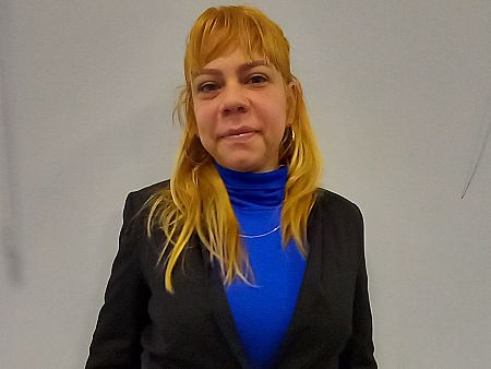 Retrato de Claudia, una mujer rubia con jersey azul y chaqueta negra, cuyo mayor deseo es volver a ver a sus hijos.