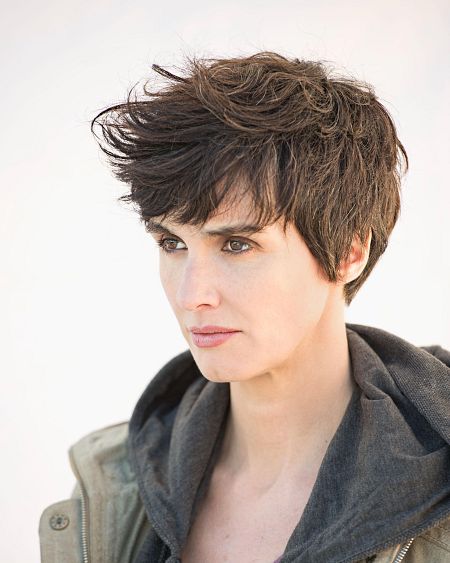 La actriz Magda Cifuentes con expresión seria, vestida con chaqueta verde militar y sudadera gris.