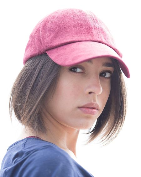 La actriz Paulina Rubio mira a la cámara con una gorra rosa y camiseta azul.