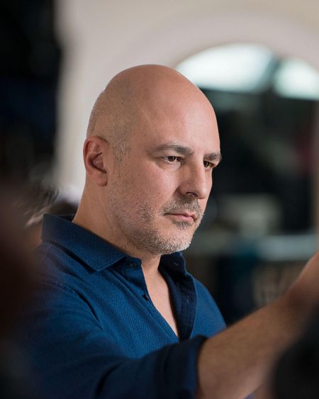 José Coronado, con camisa azul oscuro, mira con seriedad hacia la derecha.