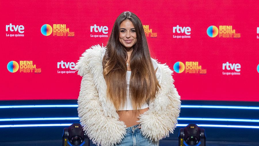 Daniela Blasco posa en la rueda de prensa del Benidorm Fest 25, con una chaqueta de pelo y top blanco.