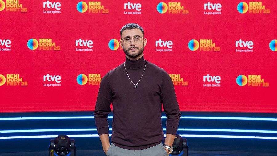 David Afonso en la rueda de prensa del Benidorm Fest 25, con un jersey granate y pantalón gris.