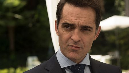 Roberto Álamo, con traje y corbata, mira con gesto serio.