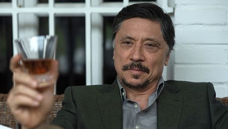 Julián Muñoz con gesto serio, observa un vaso de whisky que sujeta con la mano.